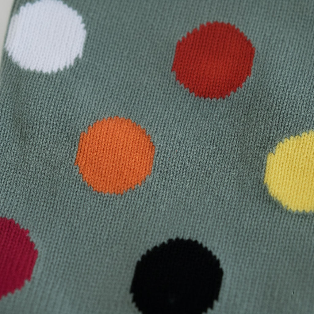 Close-up of a sock with colorful polka dots on a green background