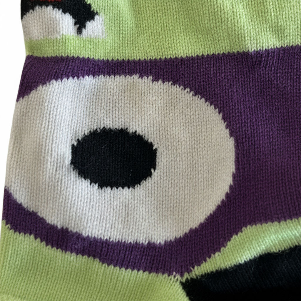 Close-up of a sock with a large eye design featuring green, purple, and white colors.