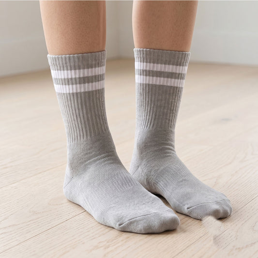 Model wearing grey ribbed crew grip socks with double stripe on a wood floor