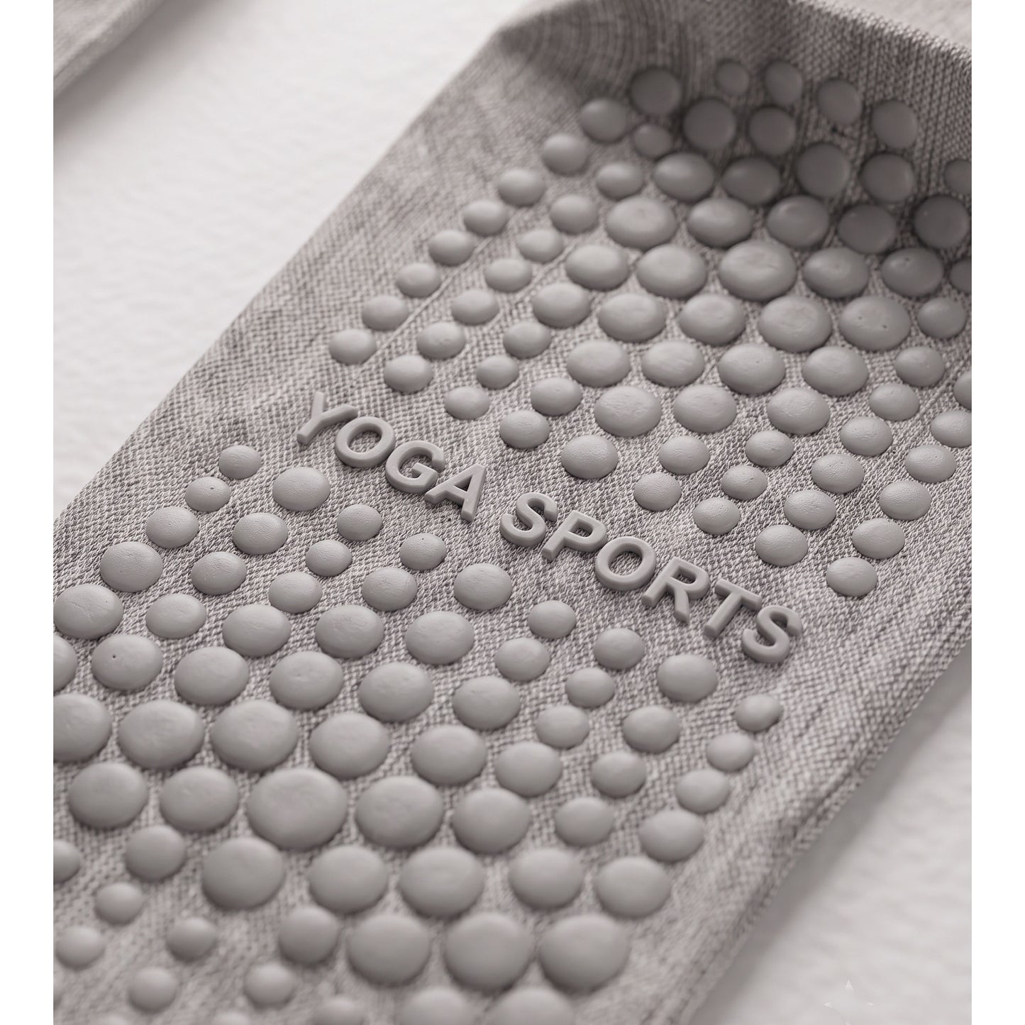 Close-up of grey grip sock sole — silicone grip dots and YOGA SPORTS text