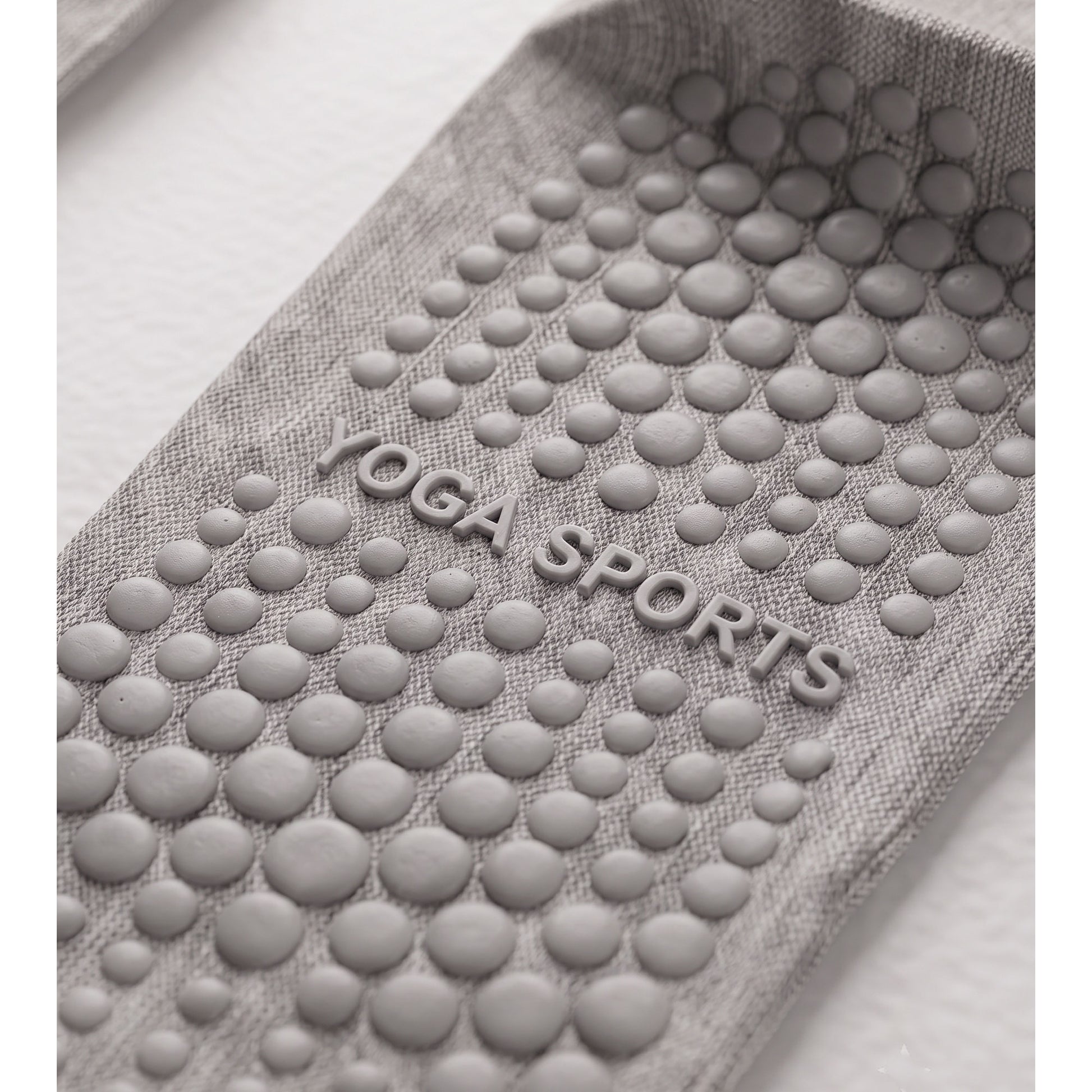 Close-up of grey grip sock sole — silicone grip dots and YOGA SPORTS text