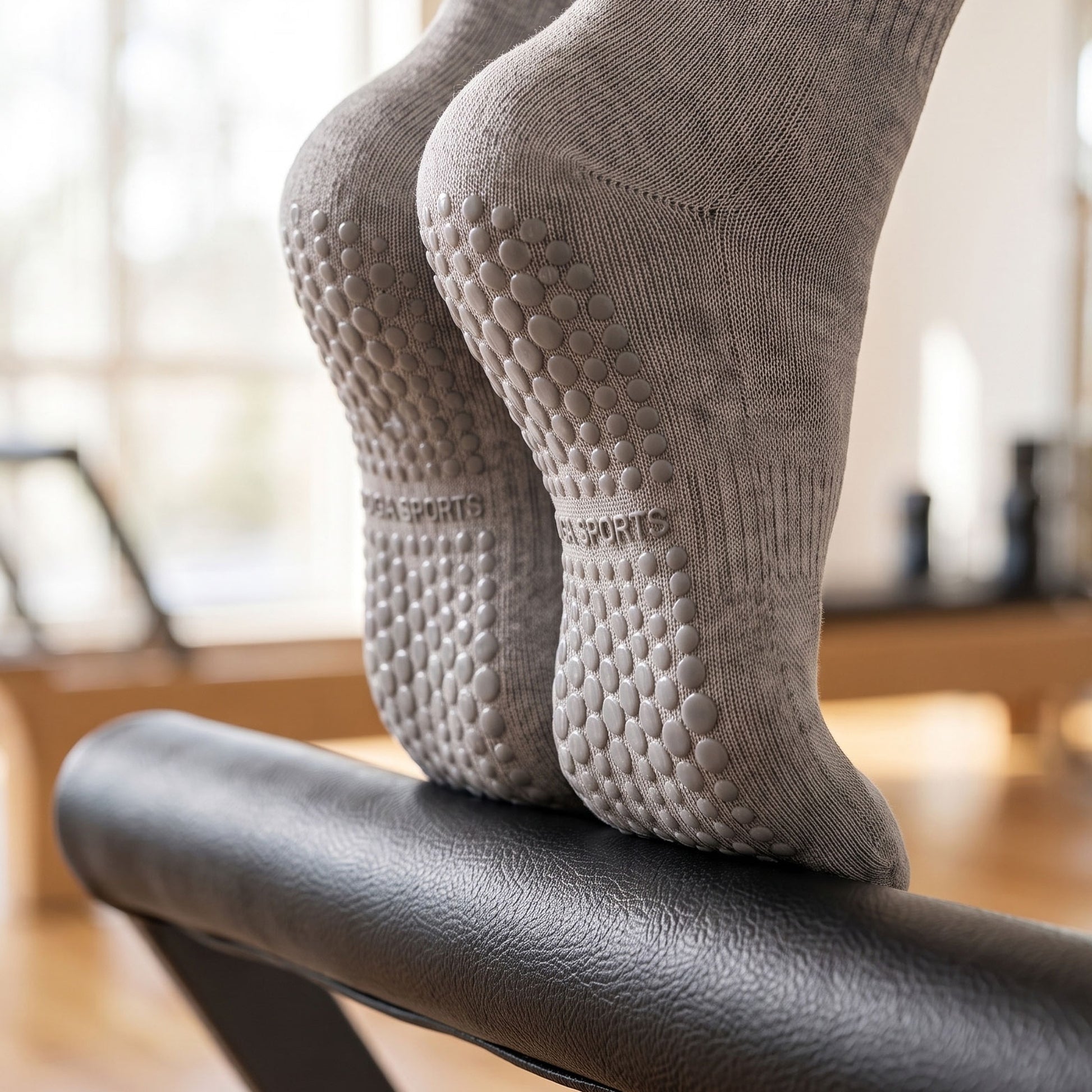 Grey crew grip socks on a pilates reformer showing non-slip silicone soles