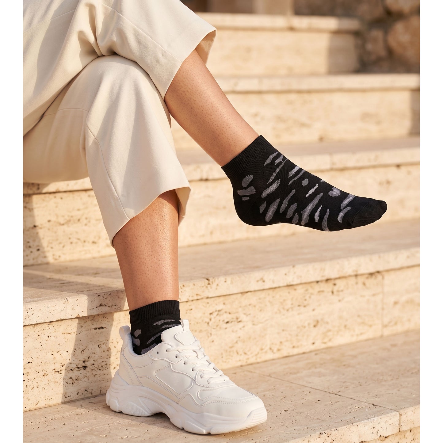 Black leopard sneaker socks with grey stitched pattern — worn with white trainers