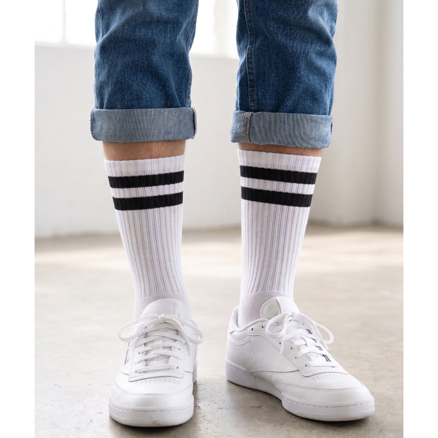 White sport crew socks with black stripes worn with white trainers and rolled jeans