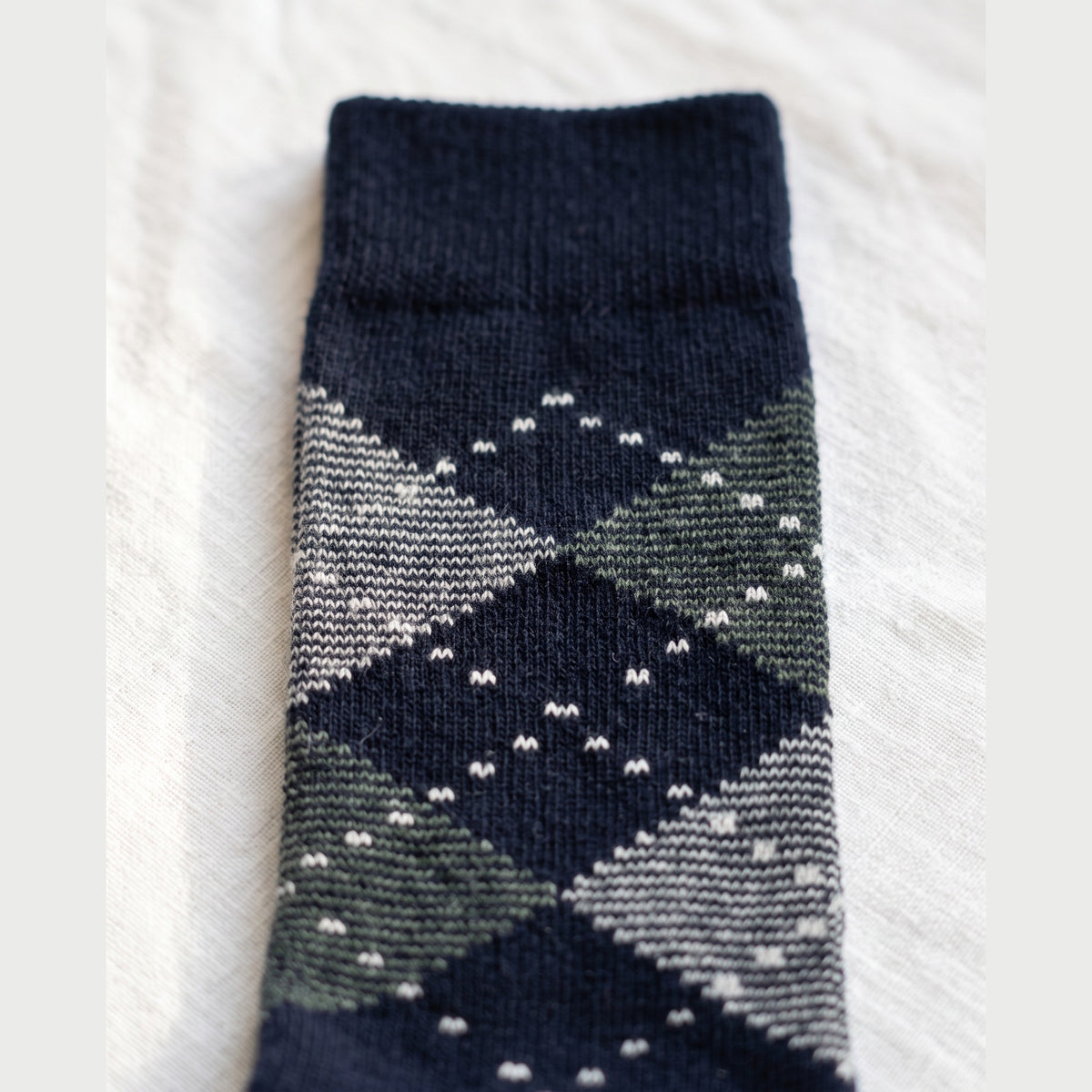 Close-up of navy argyle lambswool sock showing grey and green diamonds with white dotted outlines