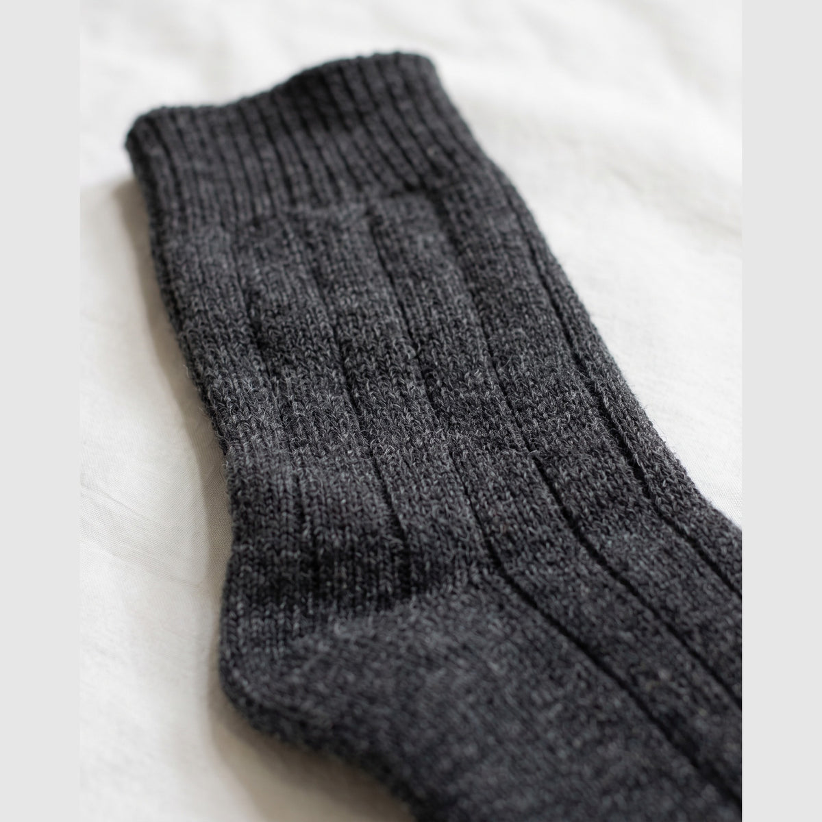 Close-up of charcoal chunky wide-rib lambswool sock showing the thick heathered knit