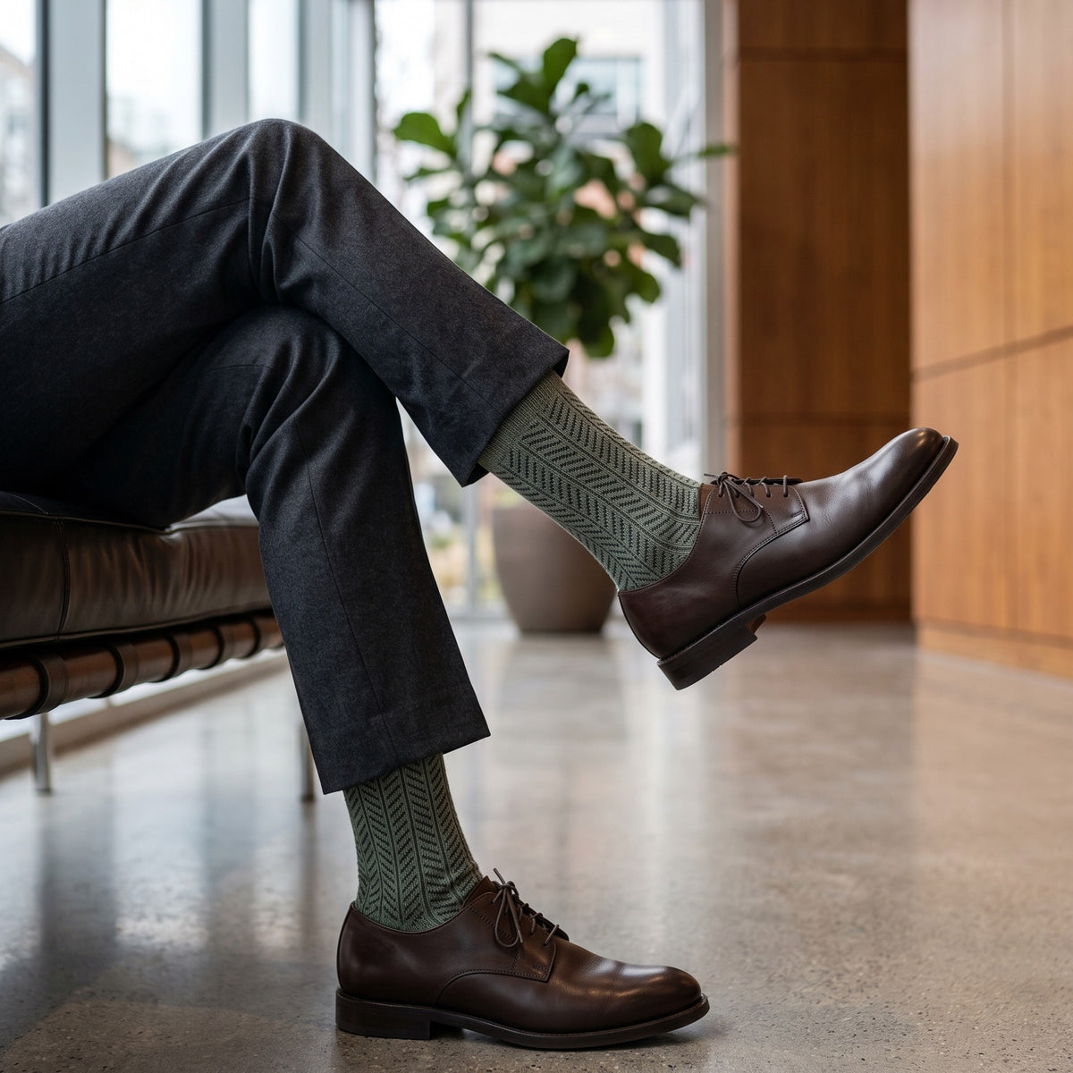 Man in an office lobby wearing khaki herringbone lambswool socks with charcoal trousers and brown derby shoes