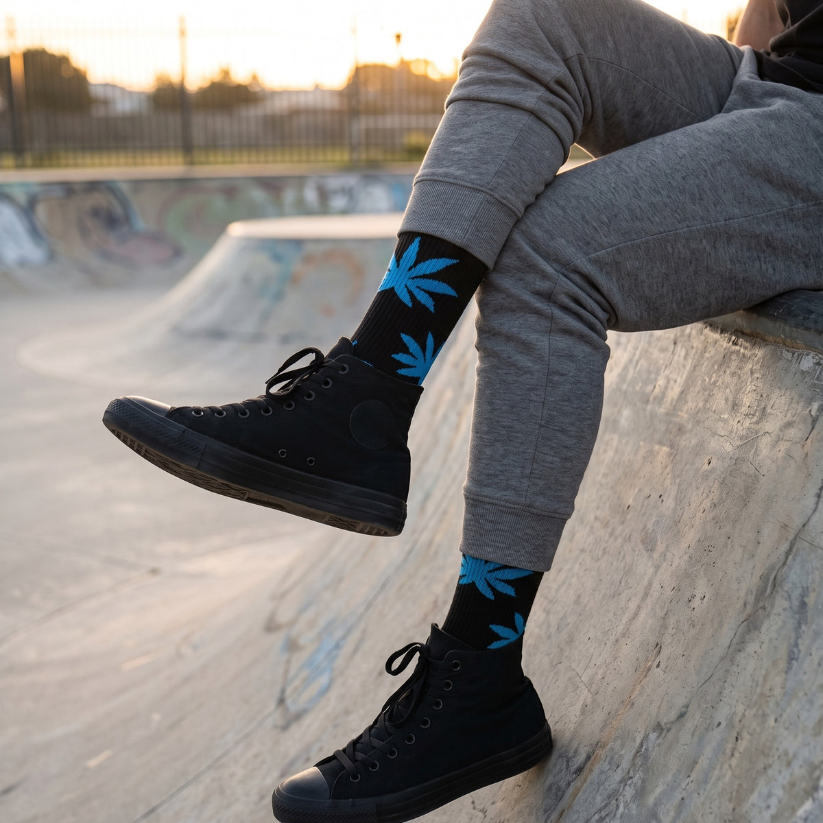 Man at a skate park wearing black leaf motif cushioned socks with grey sweatpants and black high-top sneakers