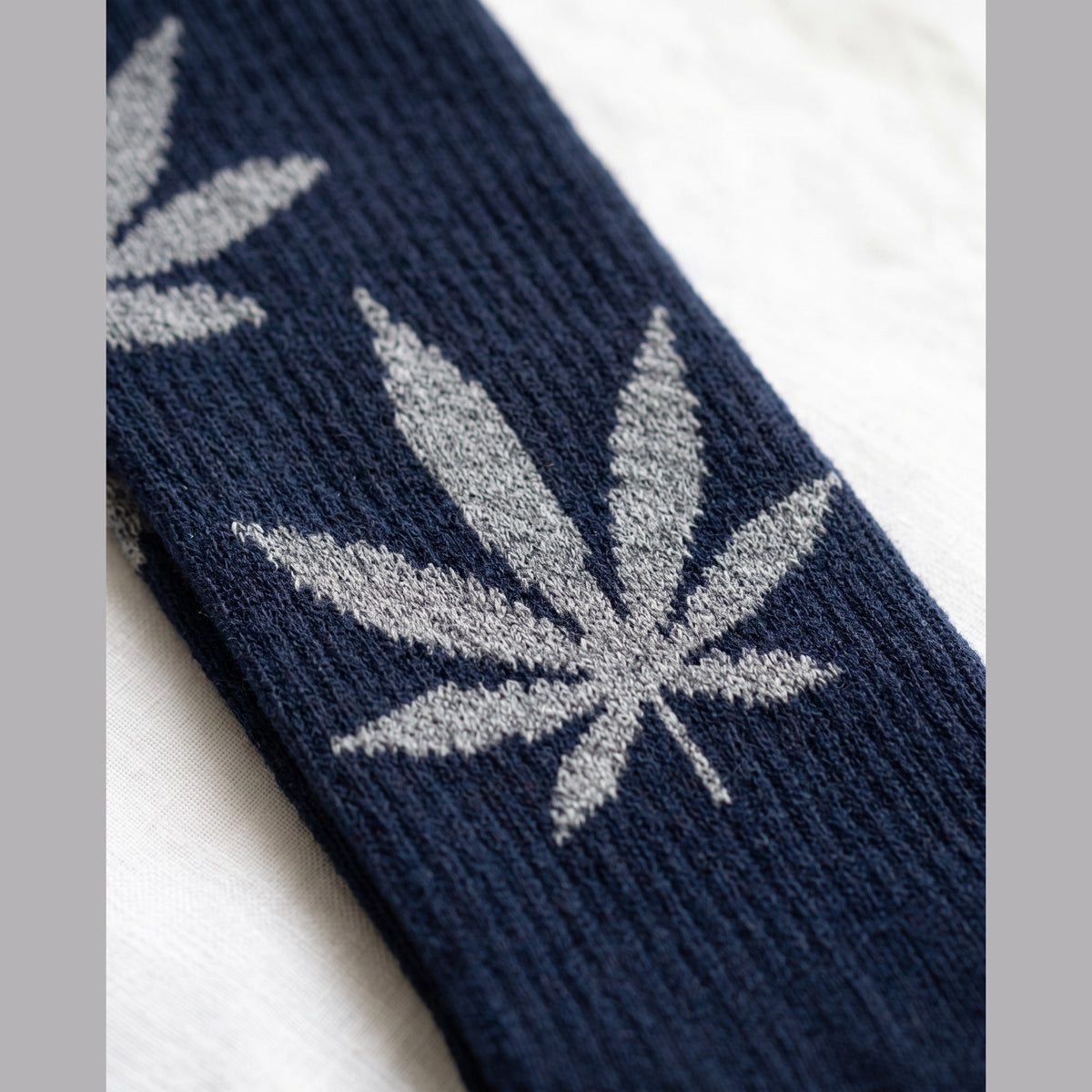 Close-up of navy sock with grey knitted leaf motifs and ribbed cuff